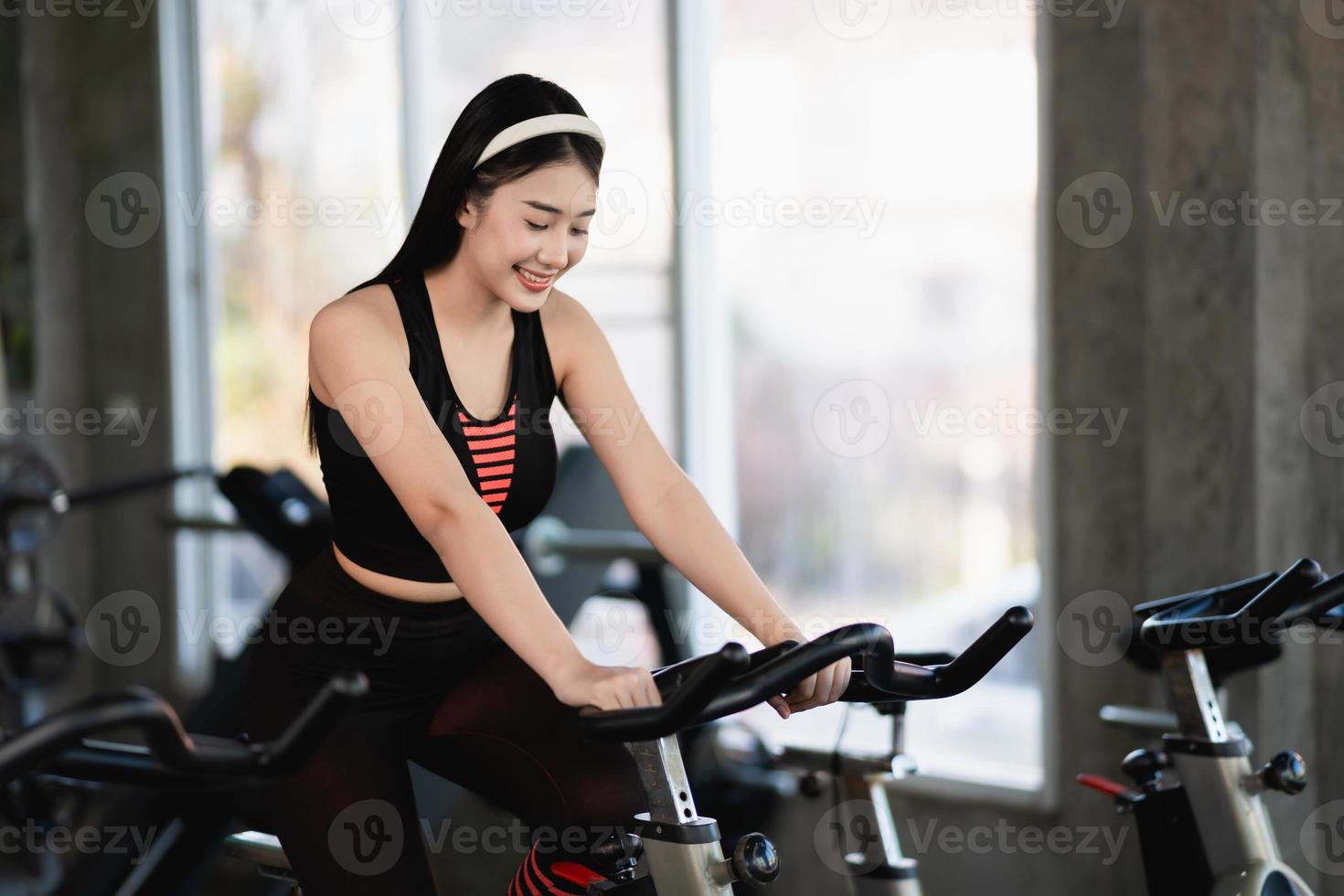 deportista asiática haciendo ejercicio en bicicleta en el gimnasio, la determinación de perder peso con cardio, la hace saludable. concepto de deporte de fitness de mujer de bicicleta de ejercicio. foto