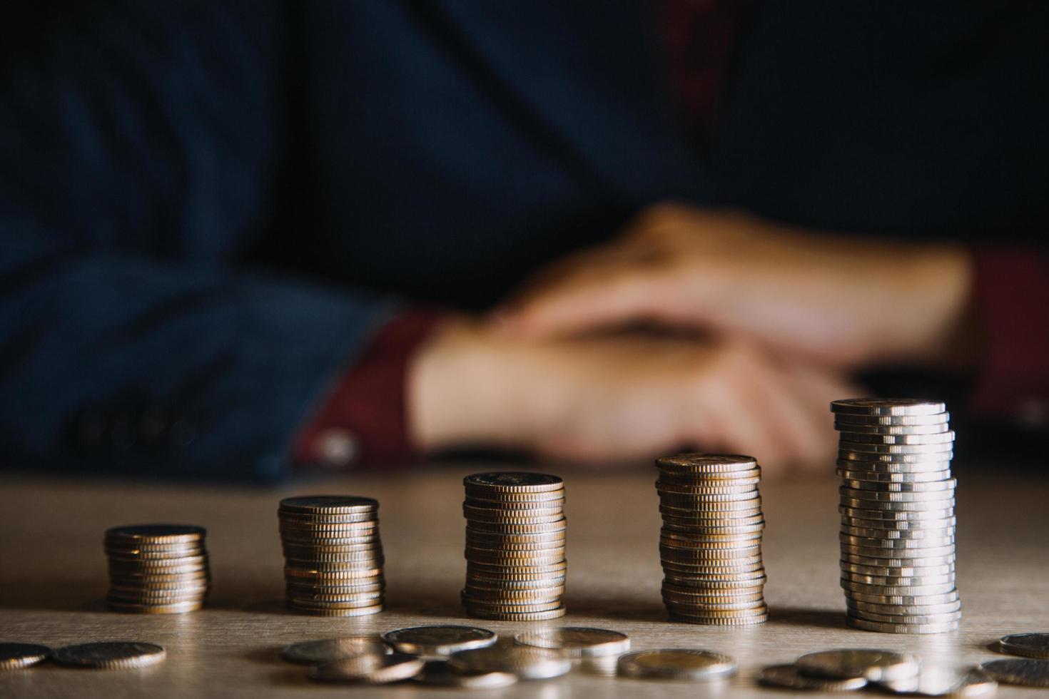 ahorrar dinero a mano poniendo monedas en la pila en la mesa con sol. concepto finanzas y contabilidad foto