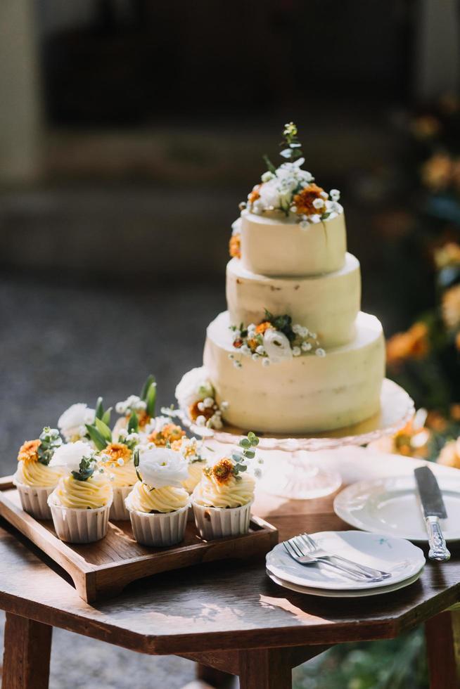 pastelitos gourmet con glaseado de crema de mantequilla blanca y chispas sobre fondo de madera foto