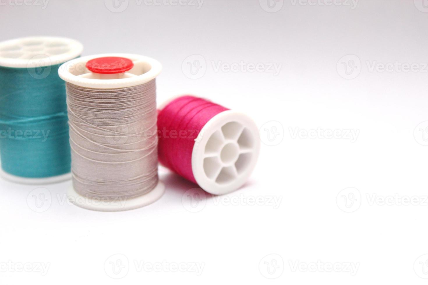 Green, red, colored thread spools placed on a white background. photo