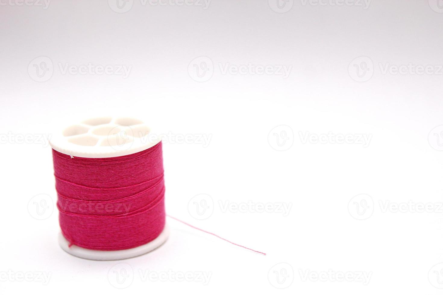 The red thread spool is placed on a white background. photo