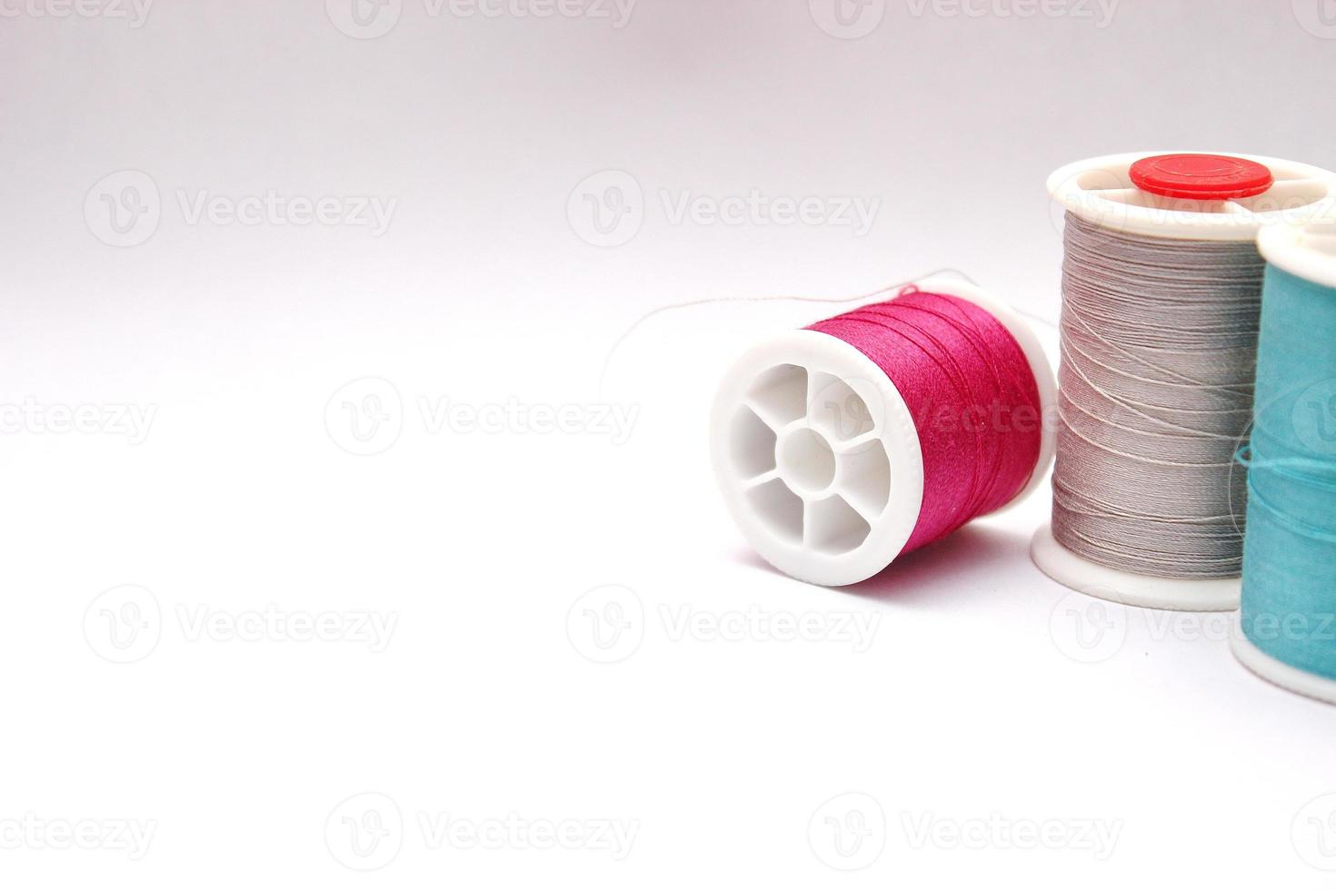 Green, red, colored thread spools placed on a white background. photo