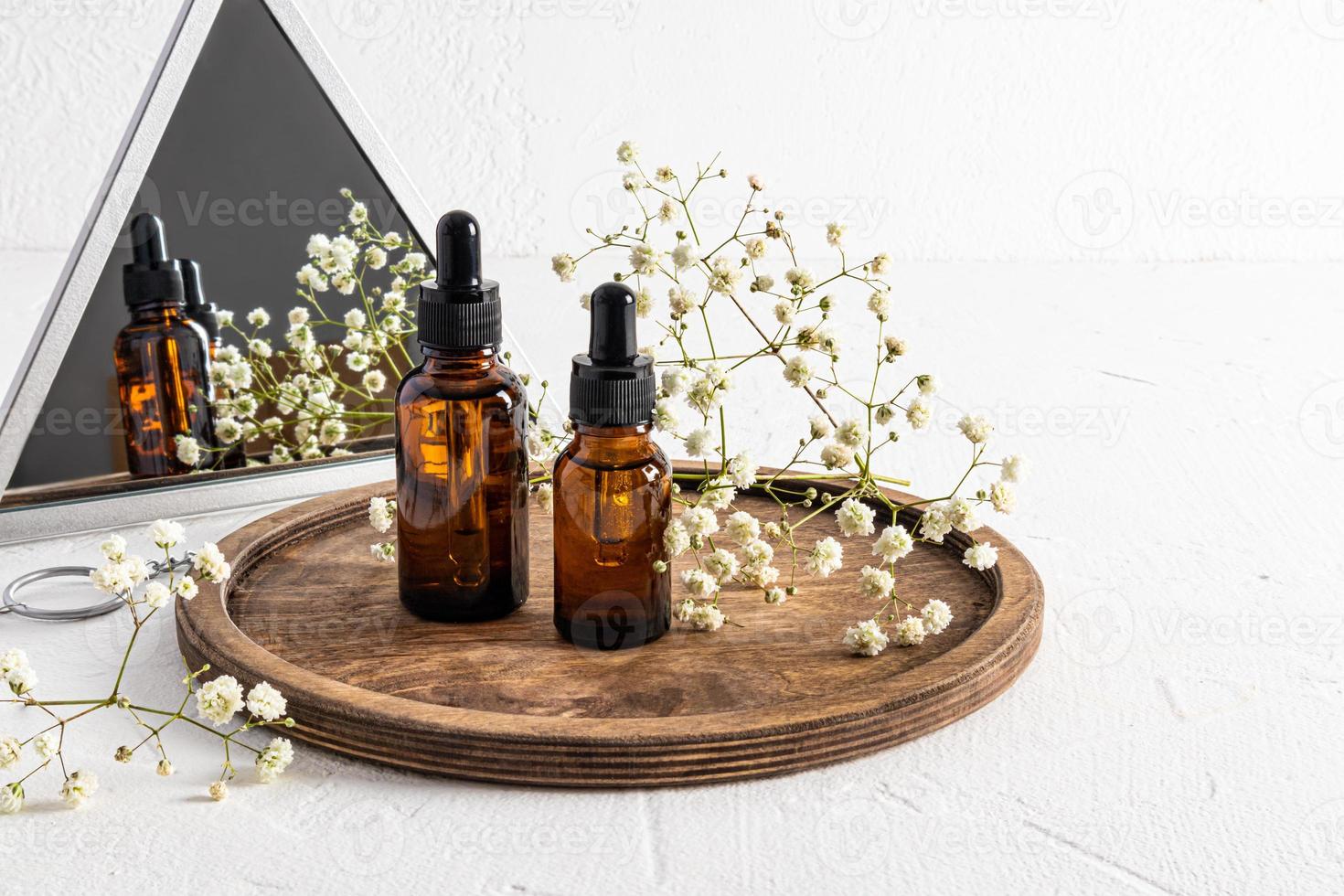 two bottles of cosmetics stand on a wooden tray with a gypsophila at the mirror. beautiful reflection in the mirror. the concept of organic self-care. photo