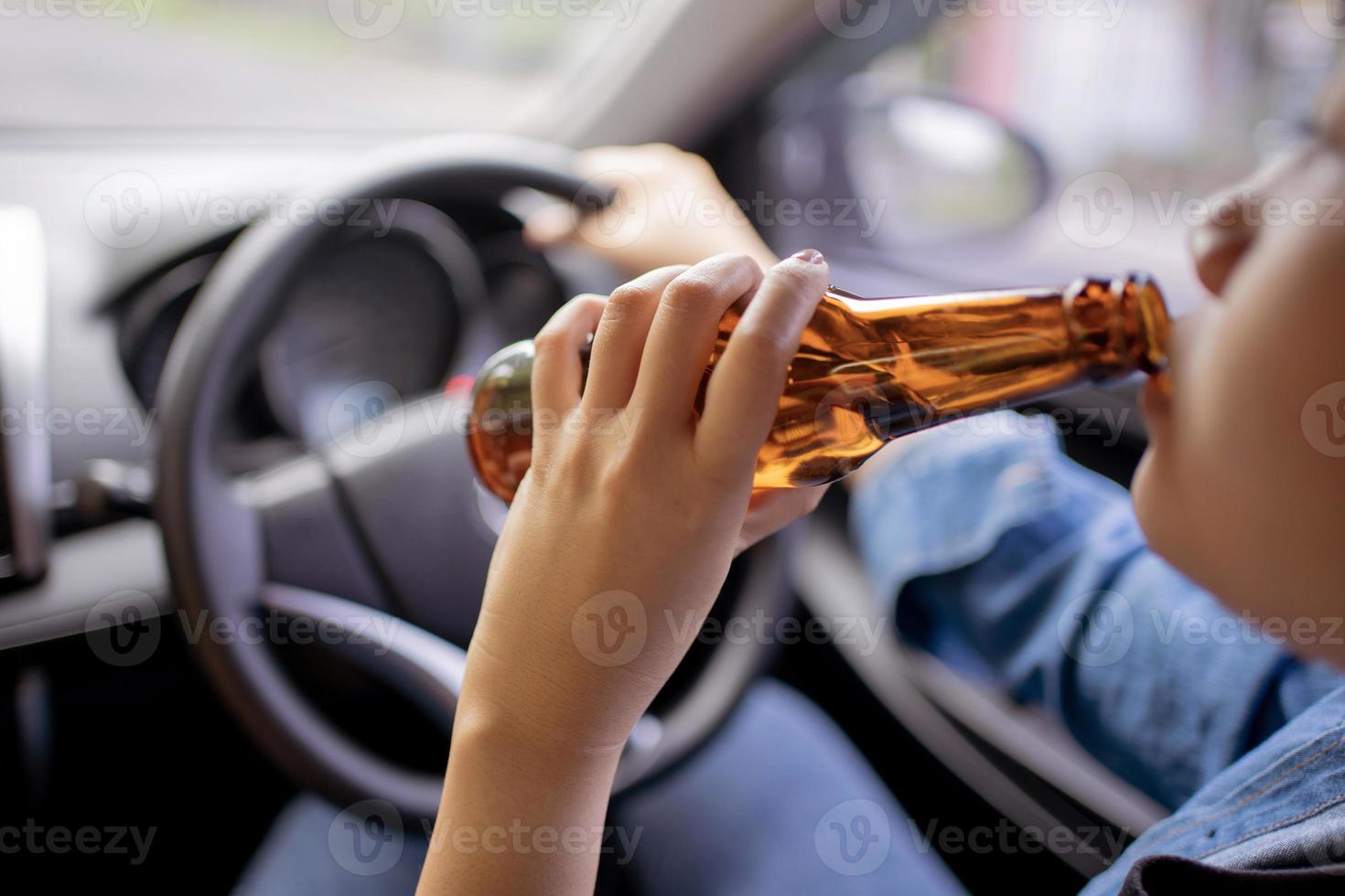 Cierra el retrato de humanos bebiendo alcohol mientras conduces. foto