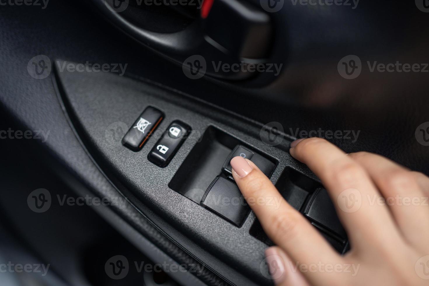 Hand pressing window buttons inside luxury car. Automatic power controlling system close-up view photo