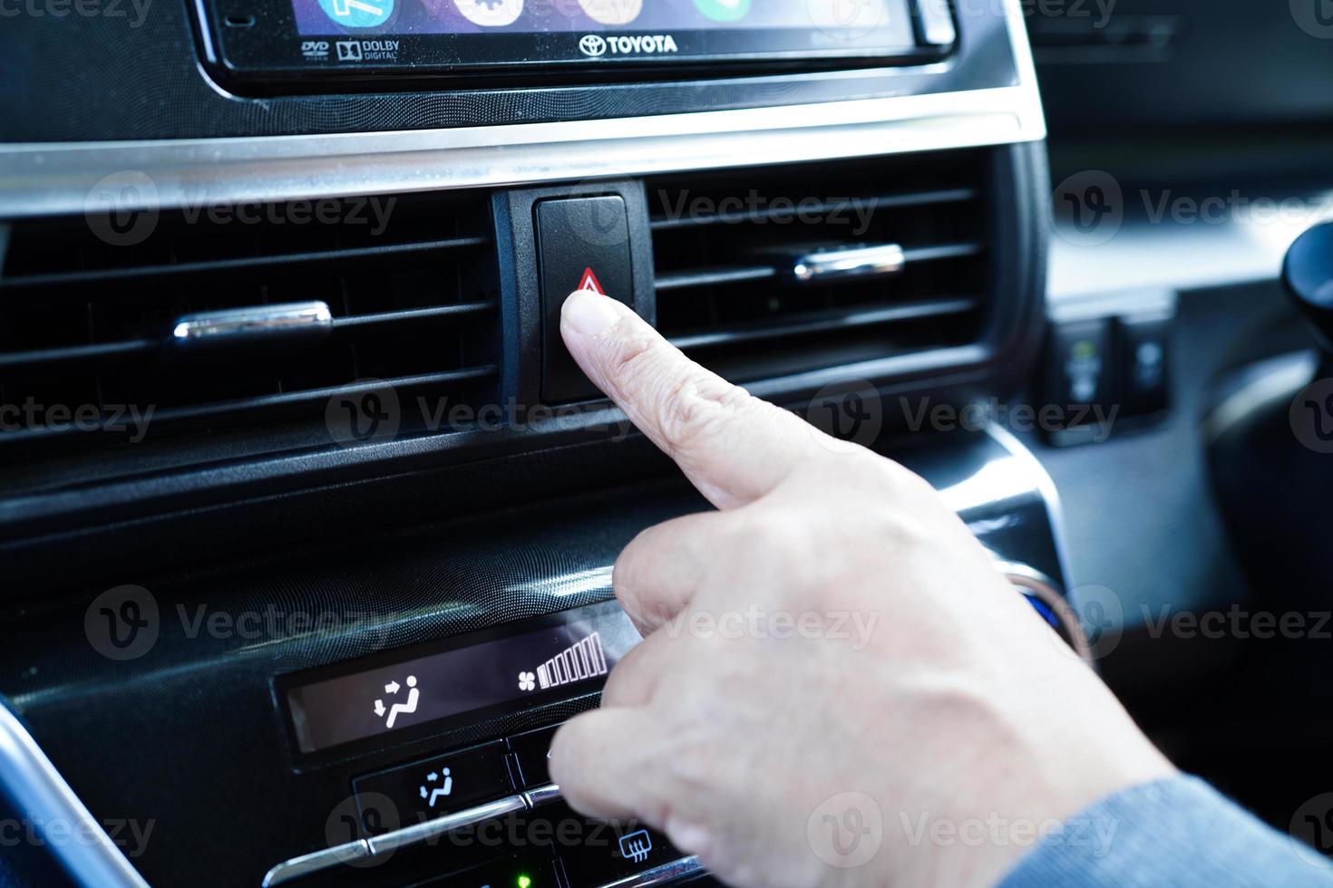 Asian woman driver pressing red emergency stop button or panic safety button on dashboard in car. photo
