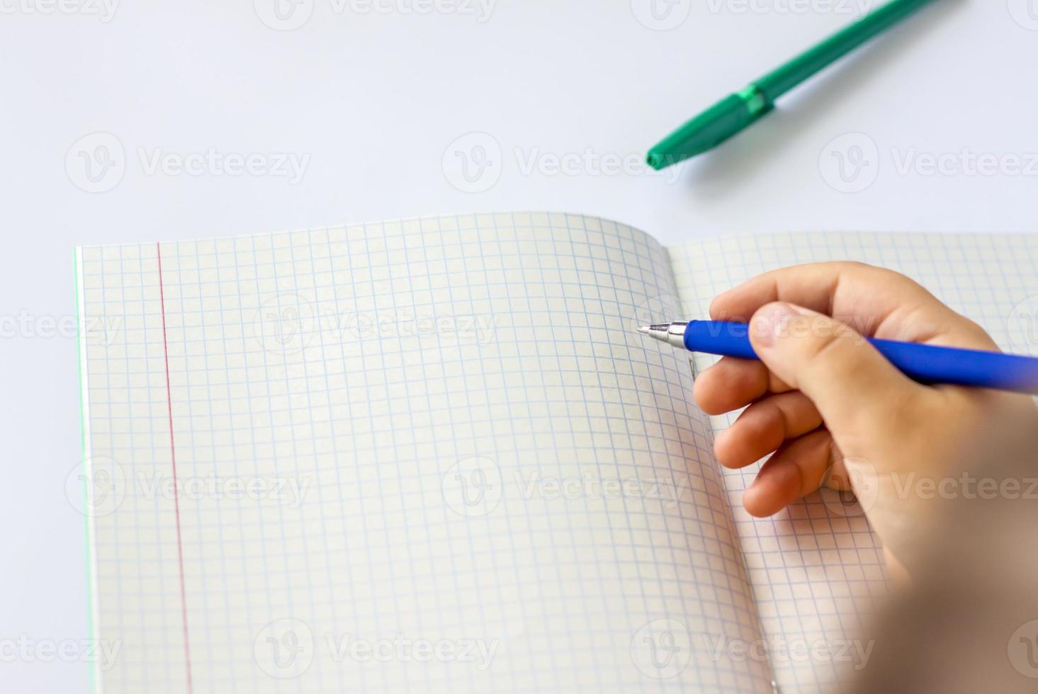 The child holds his hands over an open notebook and is going to write in it. Close-up of a child's hands. photo