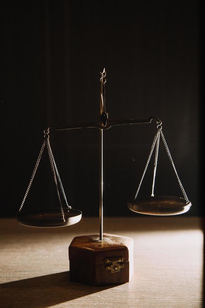 Business and lawyers discussing contract papers with brass scale on desk in office. Law, legal services, advice, justice and law concept picture with film grain effect photo