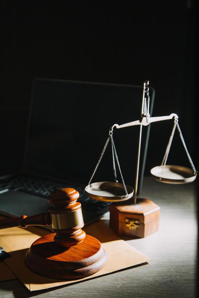 law books and scales of justice on desk in library of law firm. jurisprudence legal education concept. photo