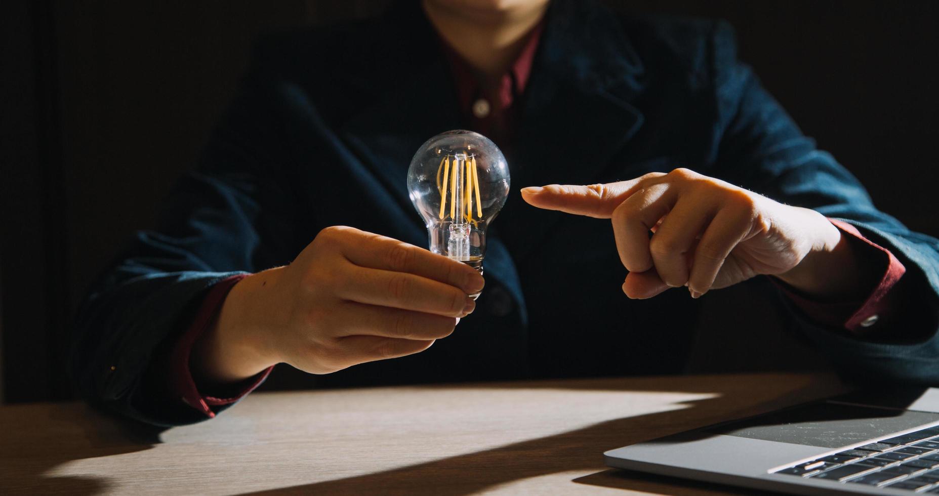 hombre de negocios tocando una bombilla de luz brillante. concepto de ideas para presentar nuevas ideas gran inspiración e innovación nuevo comienzo. foto