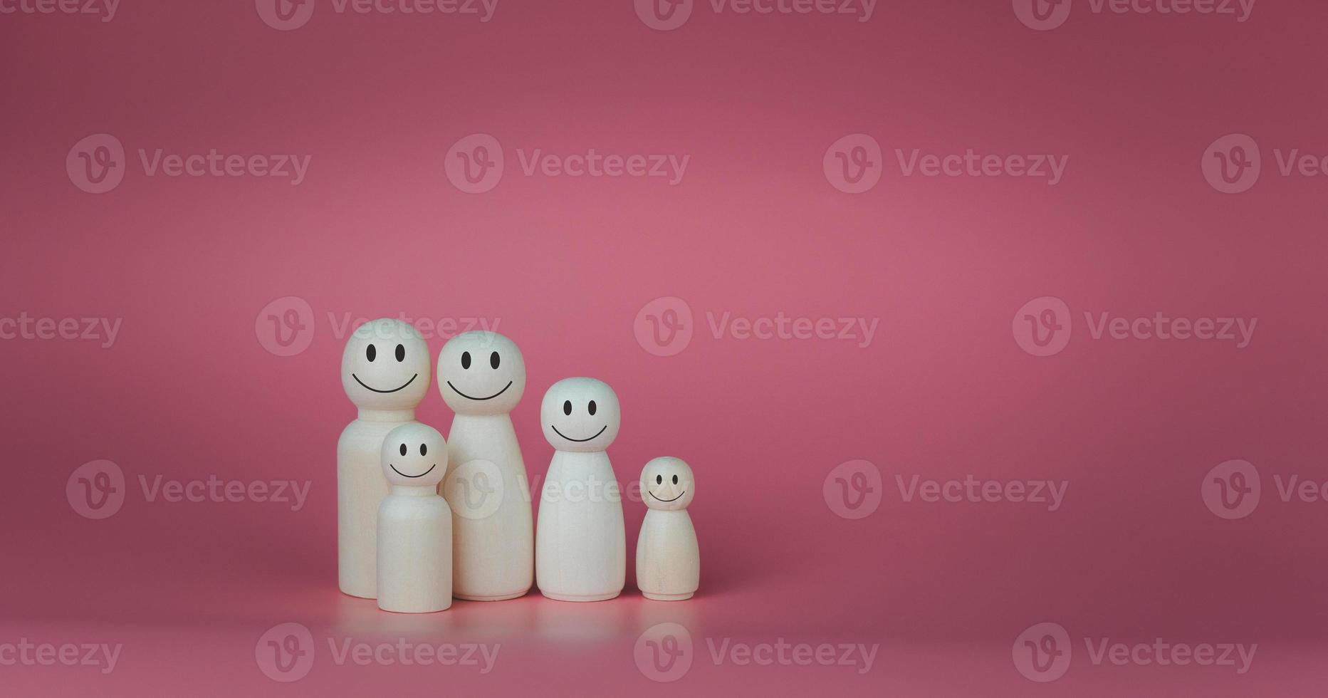 Happy house concept. Wooden dolls stand lined up against a pink background. Indicates happiness and love in the house. photo