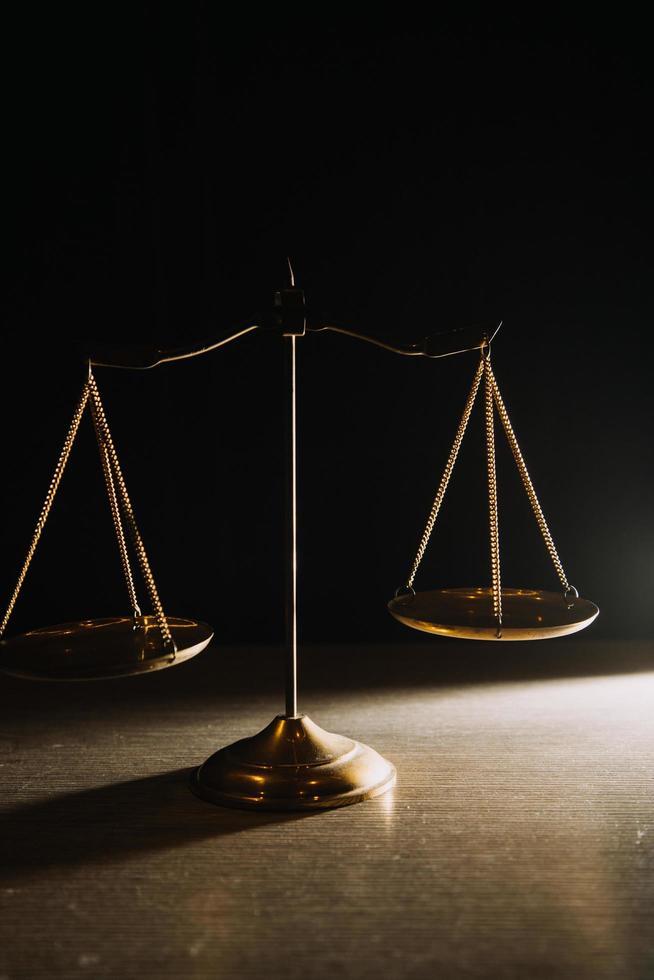 Business and lawyers discussing contract papers with brass scale on desk in office. Law, legal services, advice, justice and law concept picture with film grain effect photo