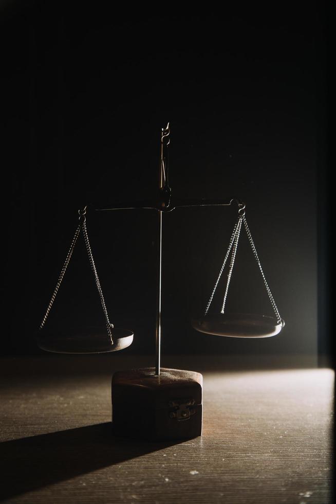 Business and lawyers discussing contract papers with brass scale on desk in office. Law, legal services, advice, justice and law concept picture with film grain effect photo