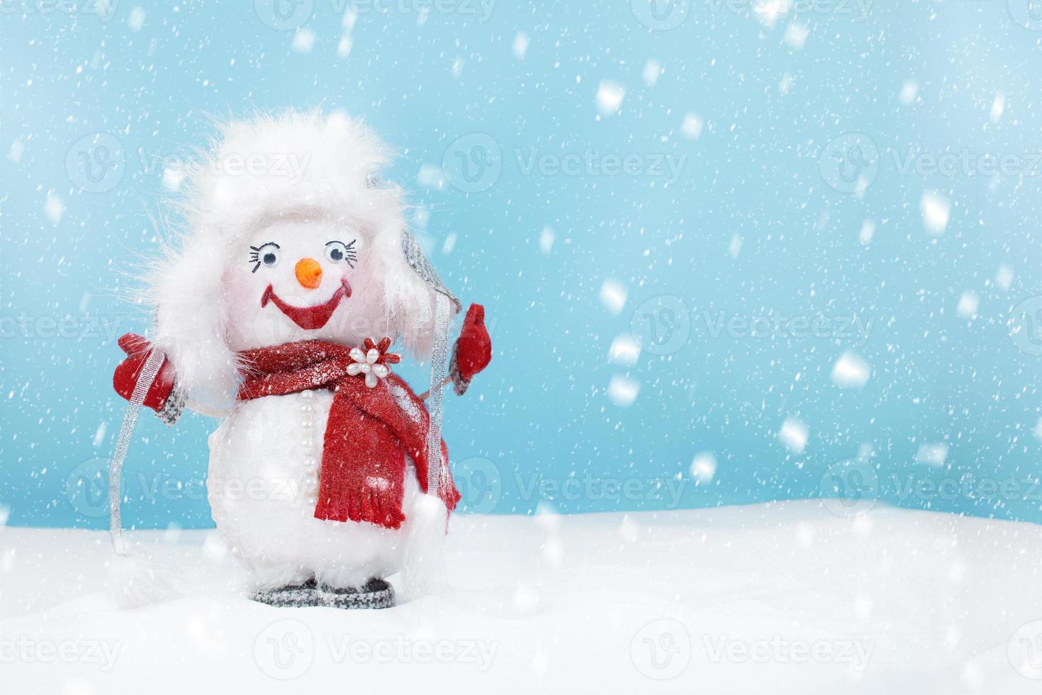 Cute happy snowman wearing fluffy hat and red scarf standing in the snow. Cartoon, funny. Christmas, New year background with winter and snowfall. Copy space photo