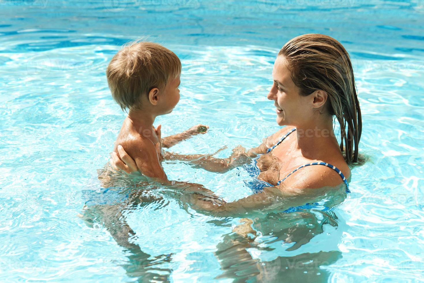 madre y su pequeño y lindo hijo nadando en la piscina al aire libre durante las vacaciones de verano foto