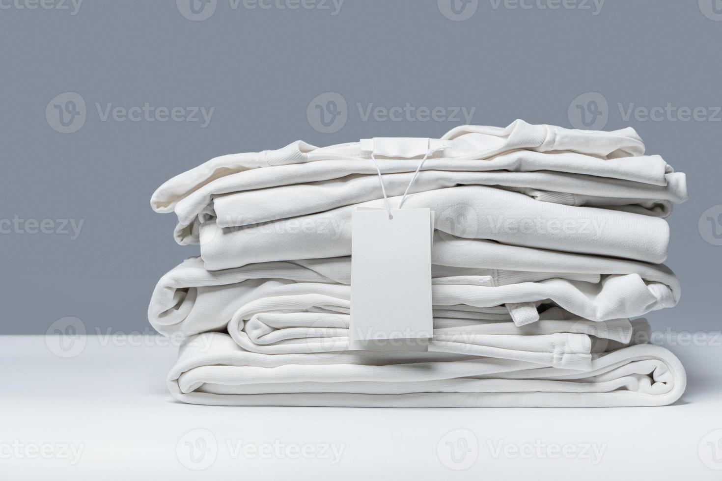 Stack of new white clothes with a blank garment tag photo