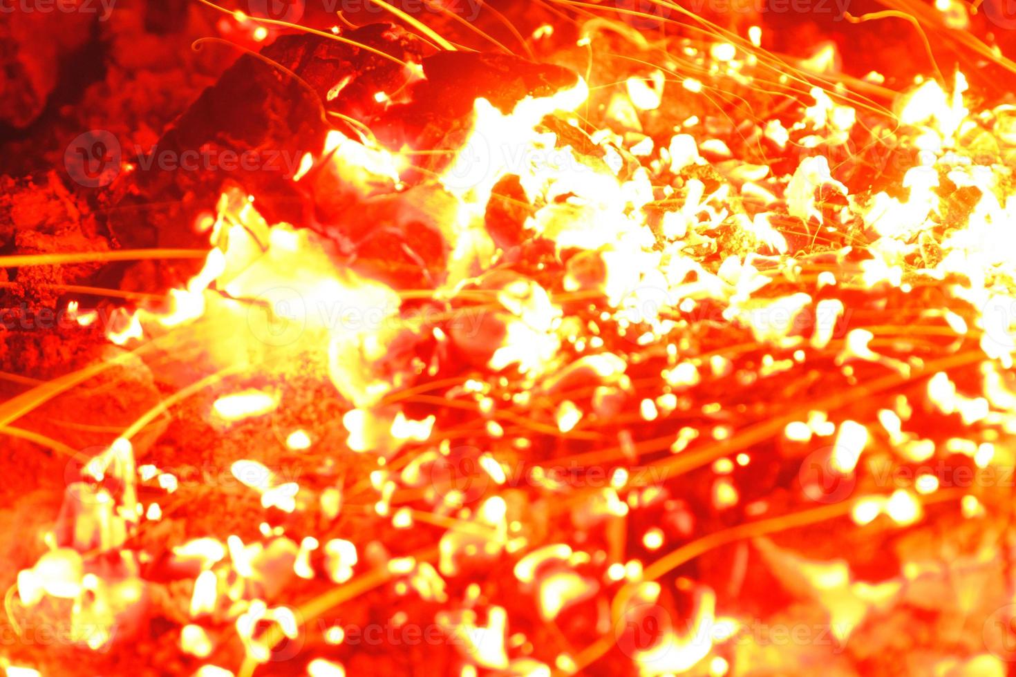 Closeup shot of campfire brightly burning at night throwing sparkles. photo