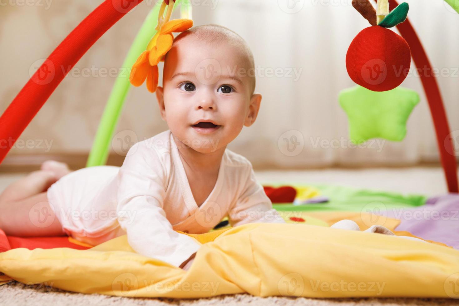 lindo bebé está jugando en la alfombra de actividades foto