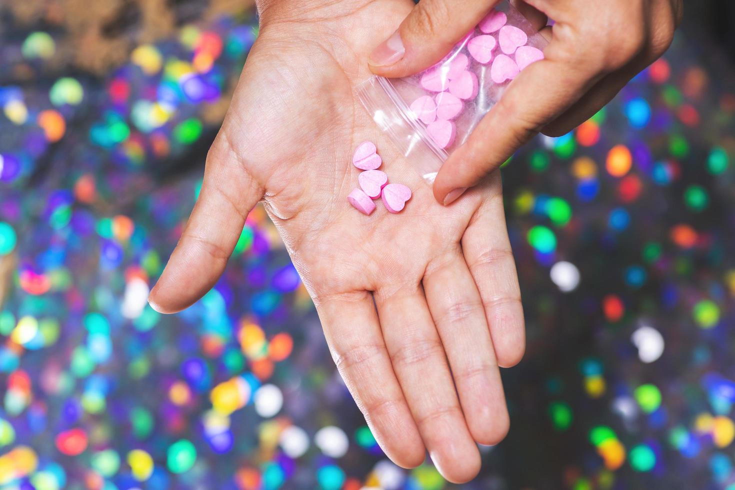 Man pouring heart shaped pills on palm from ziplock bag. photo