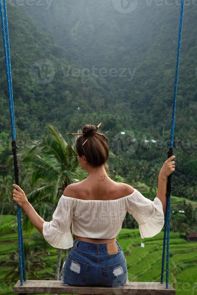Woman on rope swings with beautiful view on rice terraces in the Bali
