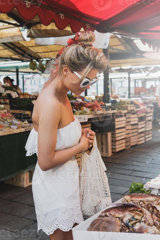 mujer con una bolsa de red durante las compras en un mercado de alimentos frescos foto