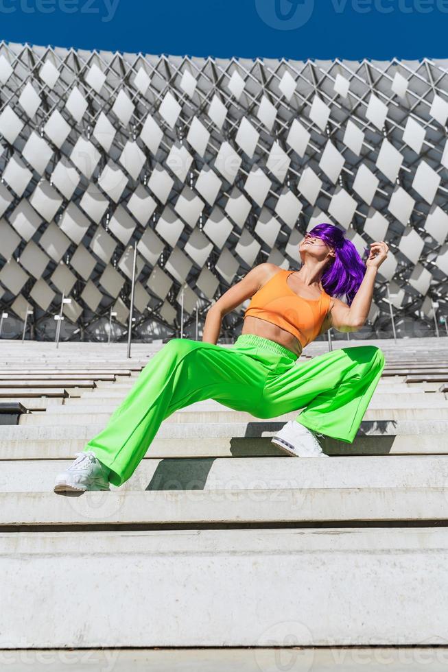 Active woman wearing colorful sportswear performing on the street during summer day photo