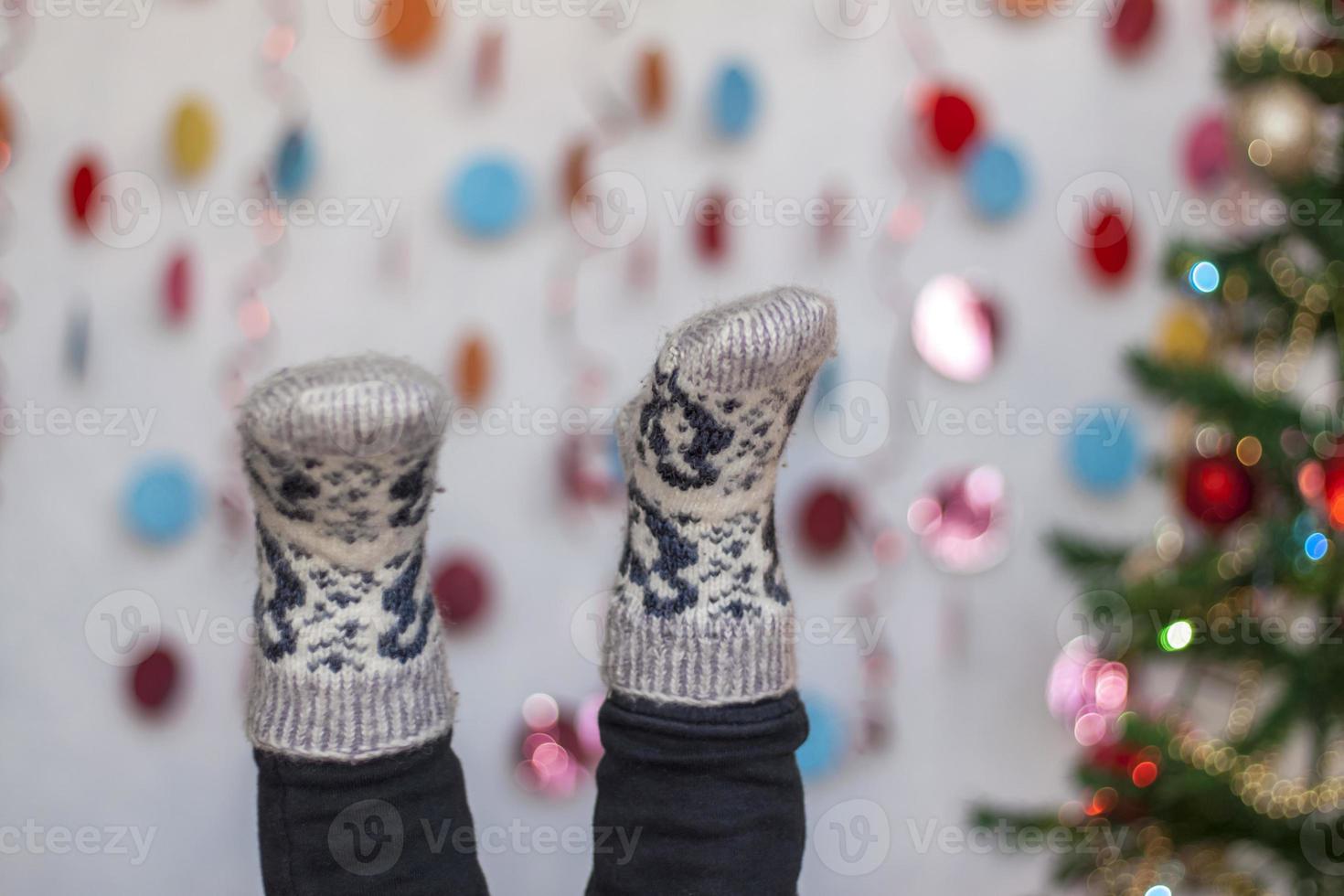 Children's feet in socks upside down and Christmas decor in the background. photo