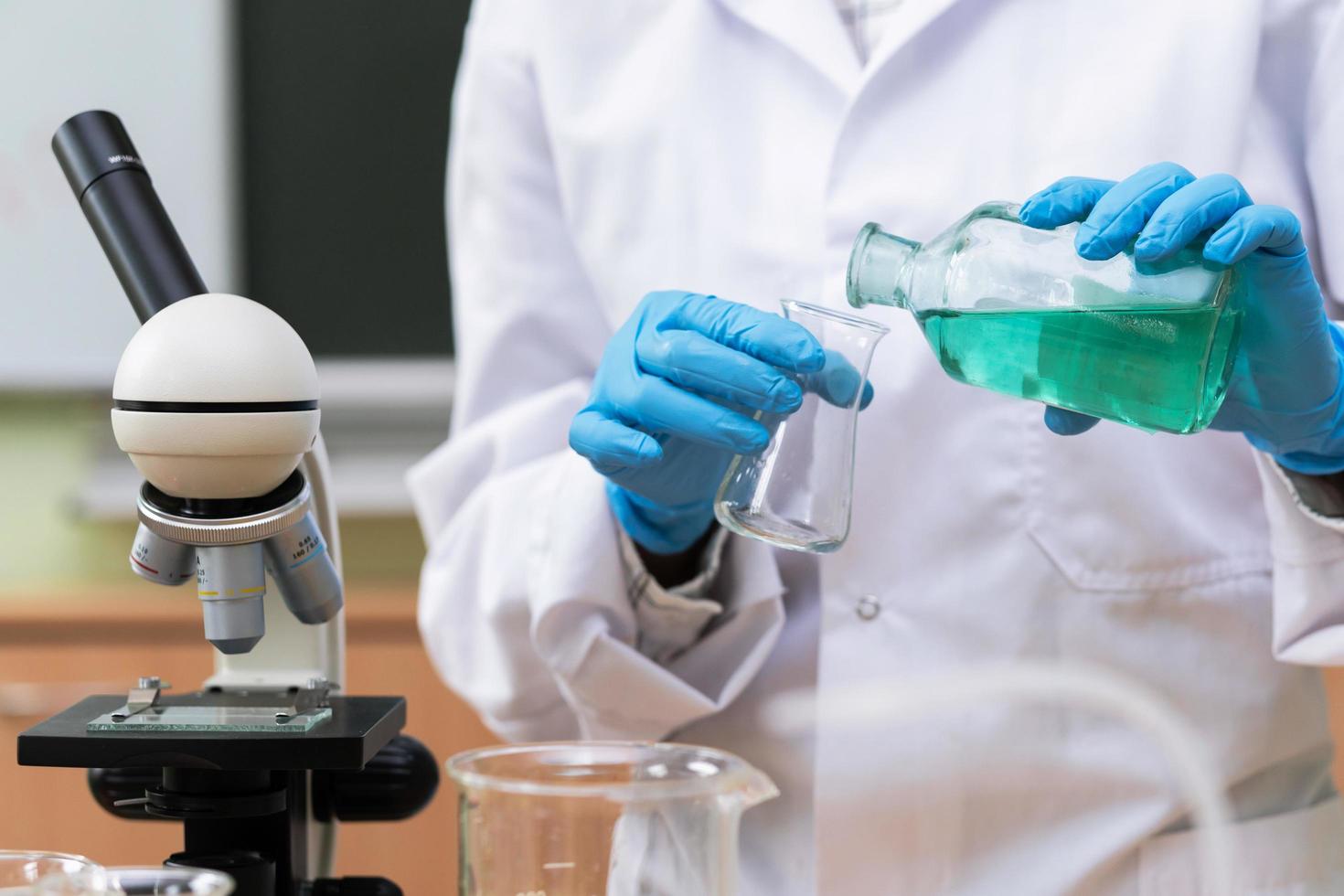 Scientist pouring substance from one flask to another in a laboratory photo