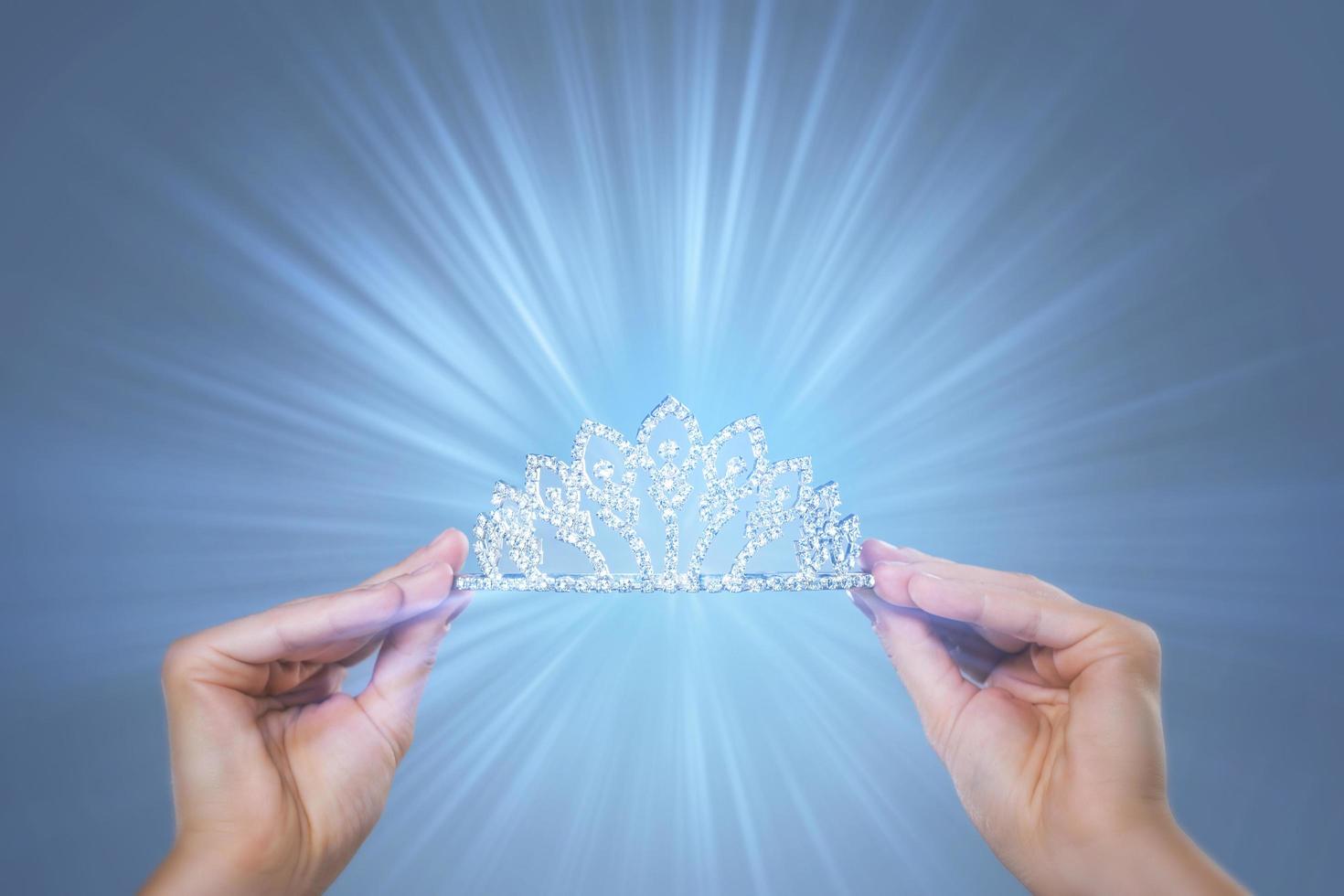 Diadem in female hands with a light rays photo