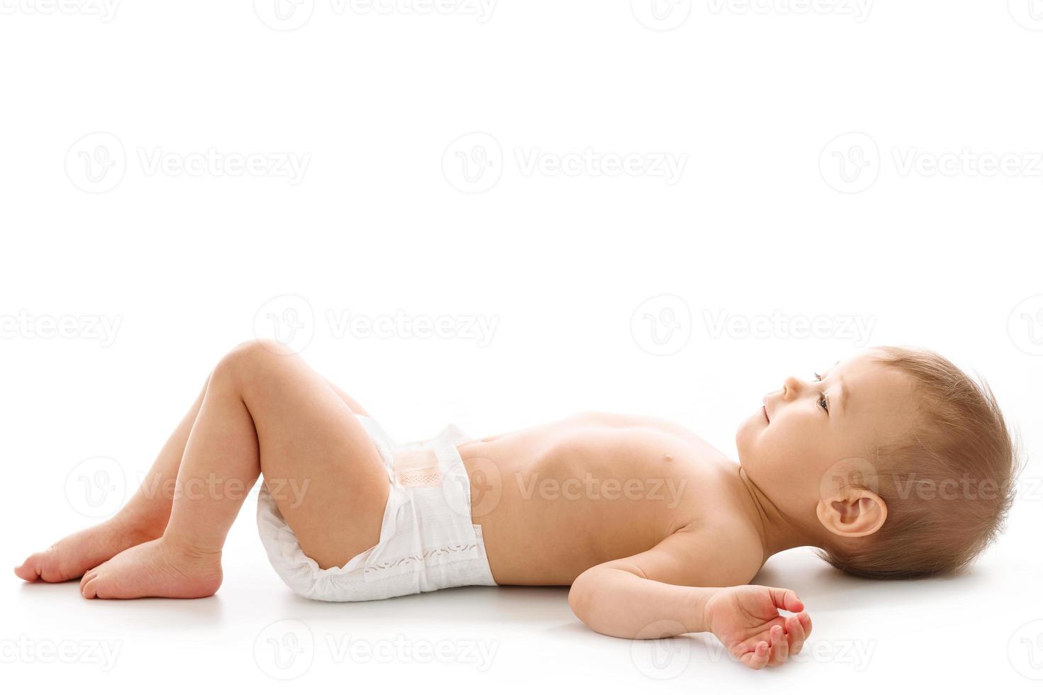 niño pequeño en pañales acostado boca arriba. foto