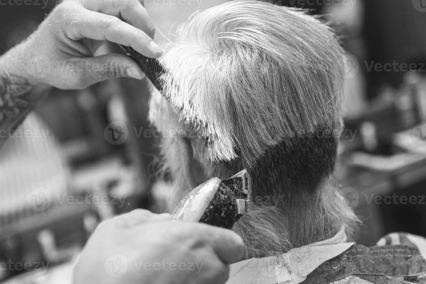 Hairdresser making stylish haircut for old man photo