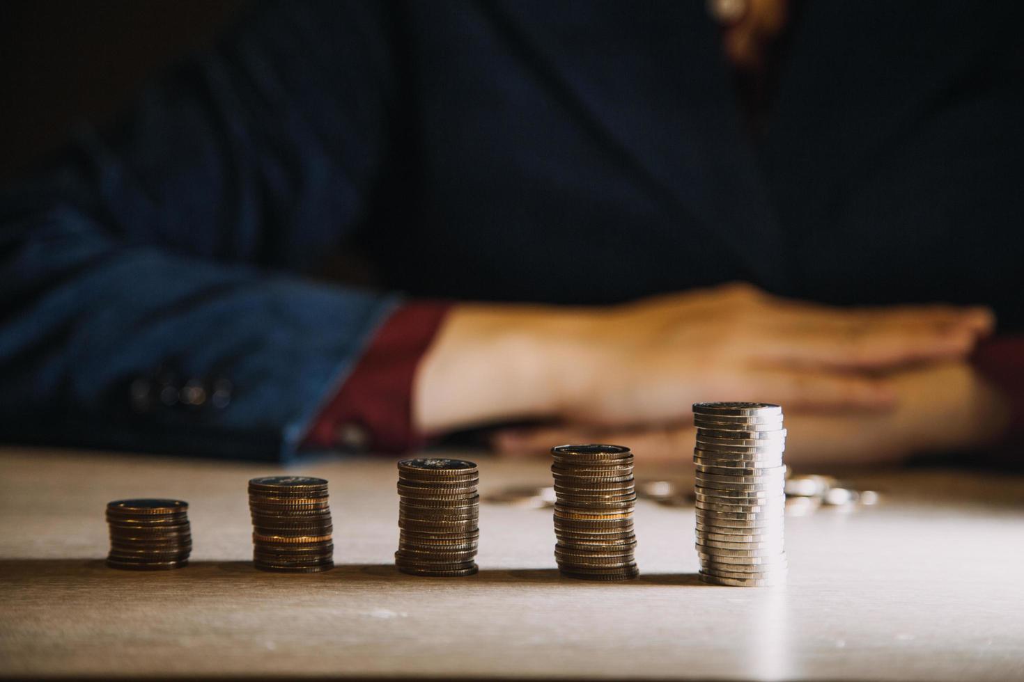 mano de mujer de negocios calculando su dinero a fin de mes con moneda, calculadora y calendario en mesa de madera foto