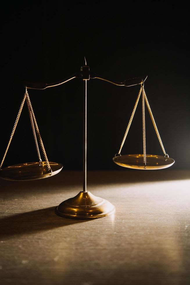 Business and lawyers discussing contract papers with brass scale on desk in office. Law, legal services, advice, justice and law concept picture with film grain effect photo