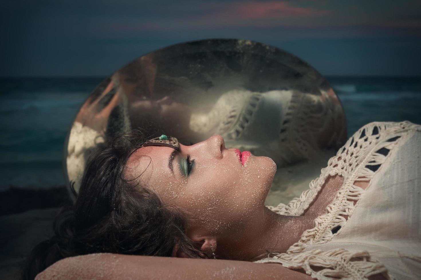 bella mujer tumbada en la playa junto a un espejo foto