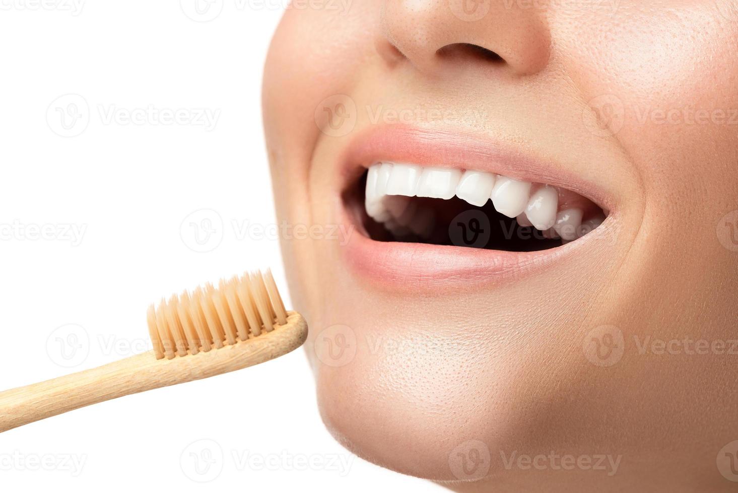 Female mouth with white teeth and bamboo toothbrush photo