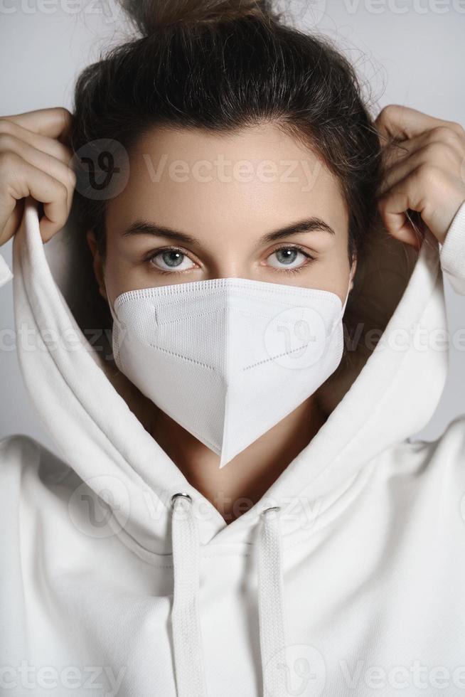 Young woman wearing white hoodie and ffp2 respirator mask photo