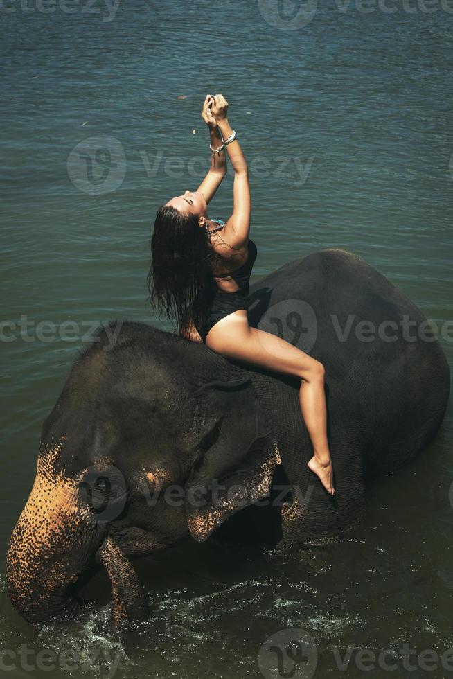 mujer feliz se está bañando con el elefante en el río foto
