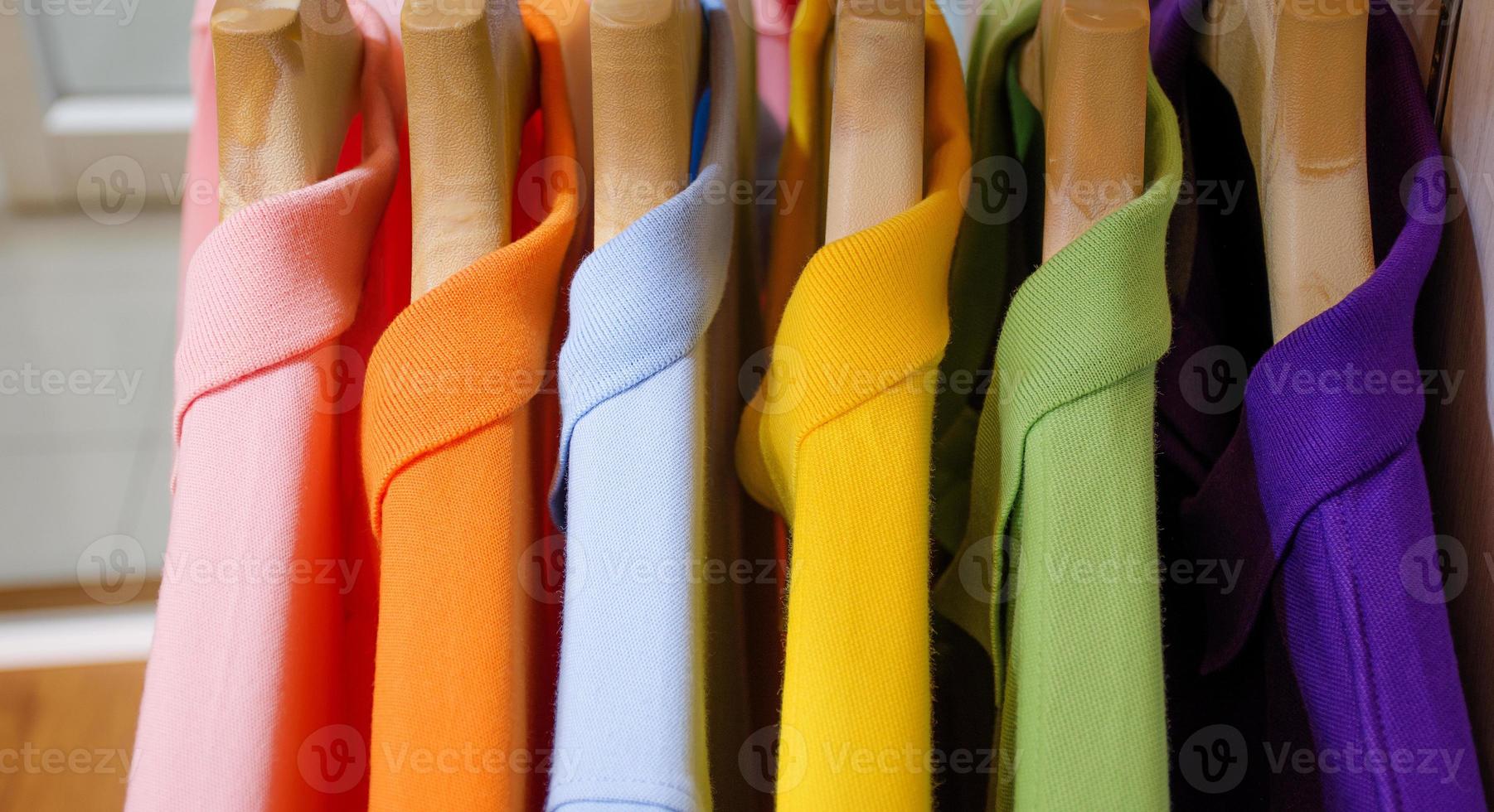 muchas camisas coloridas colgadas en un estante foto