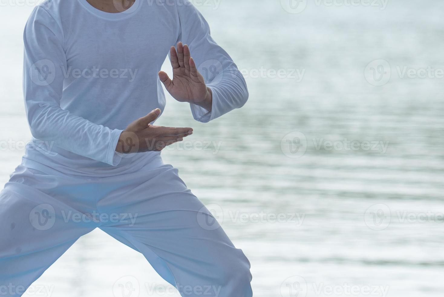 Young man practicing traditional Tai Chi Chuan, Tai Ji  and Qi gong in the park for healthy, traditional chinese martial arts concept on natural background . photo