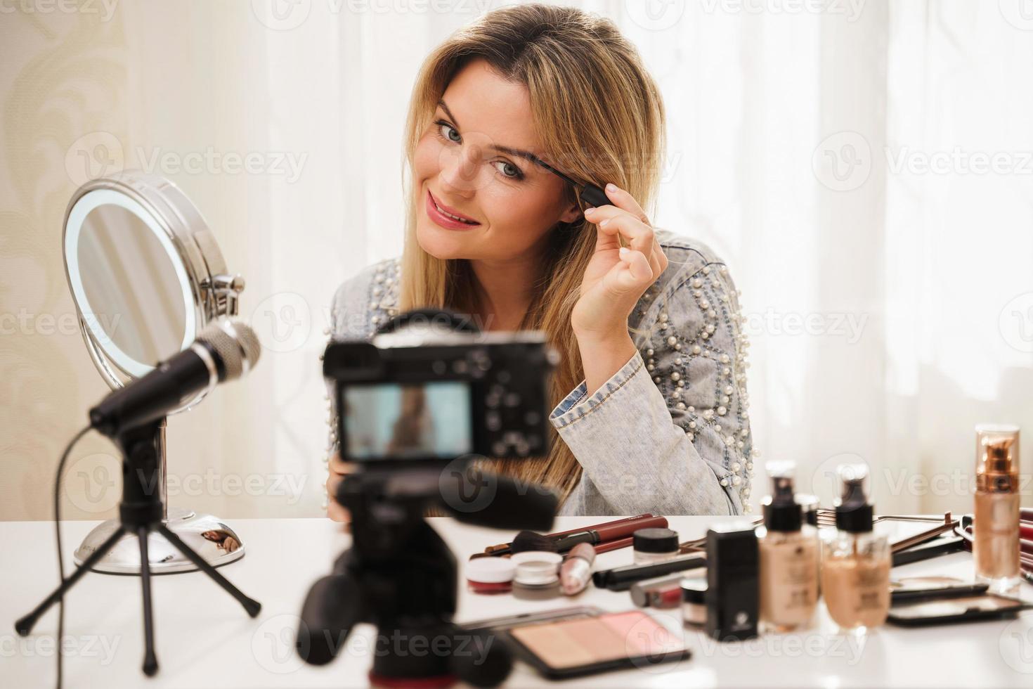 blogger de belleza mujer usando gel de tinte de cejas durante la grabación de video para sus seguidores foto