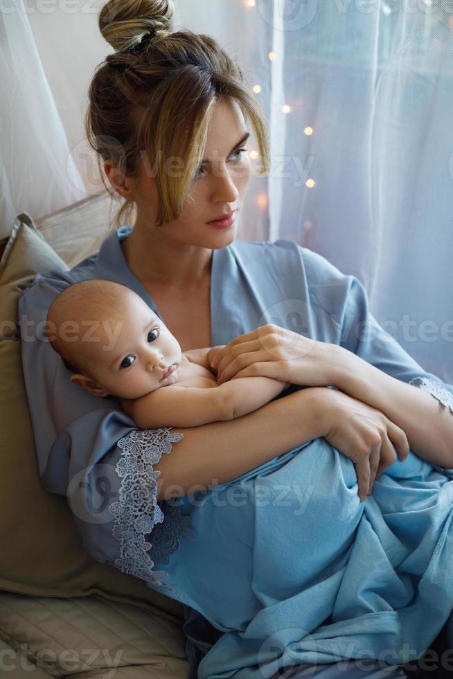 Young beautiful mother with her cute little baby wrapped in the blue cloth photo