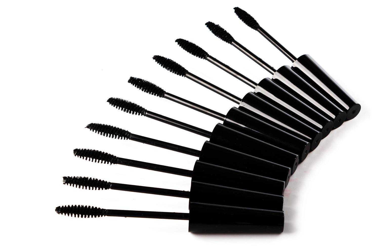 A lot of black Mascara wands on white background photo
