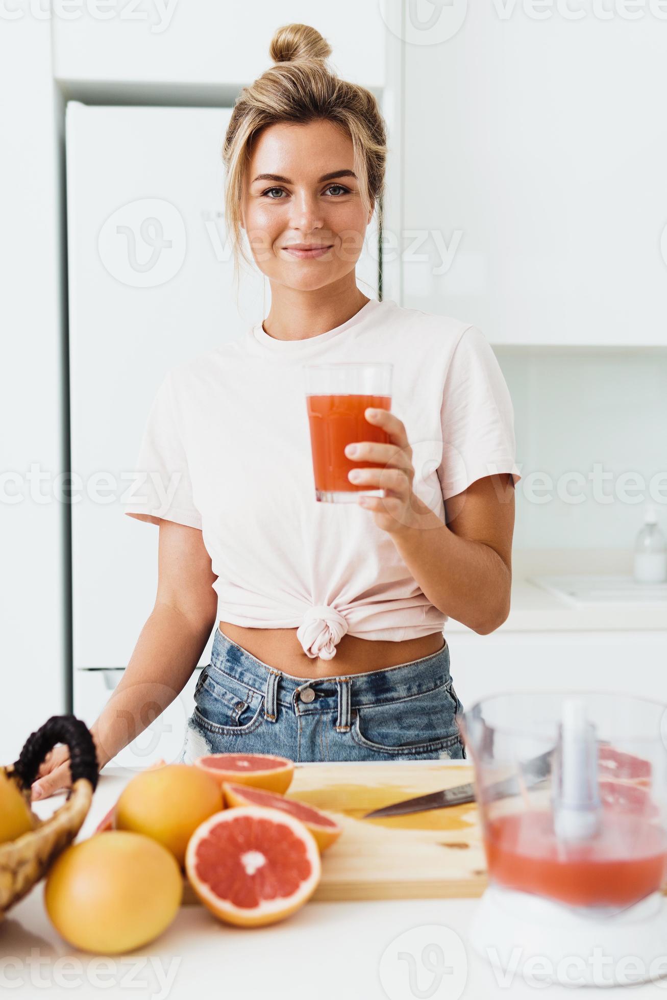 Woman drinking freshly squeezed homemade grapefruit juice in white