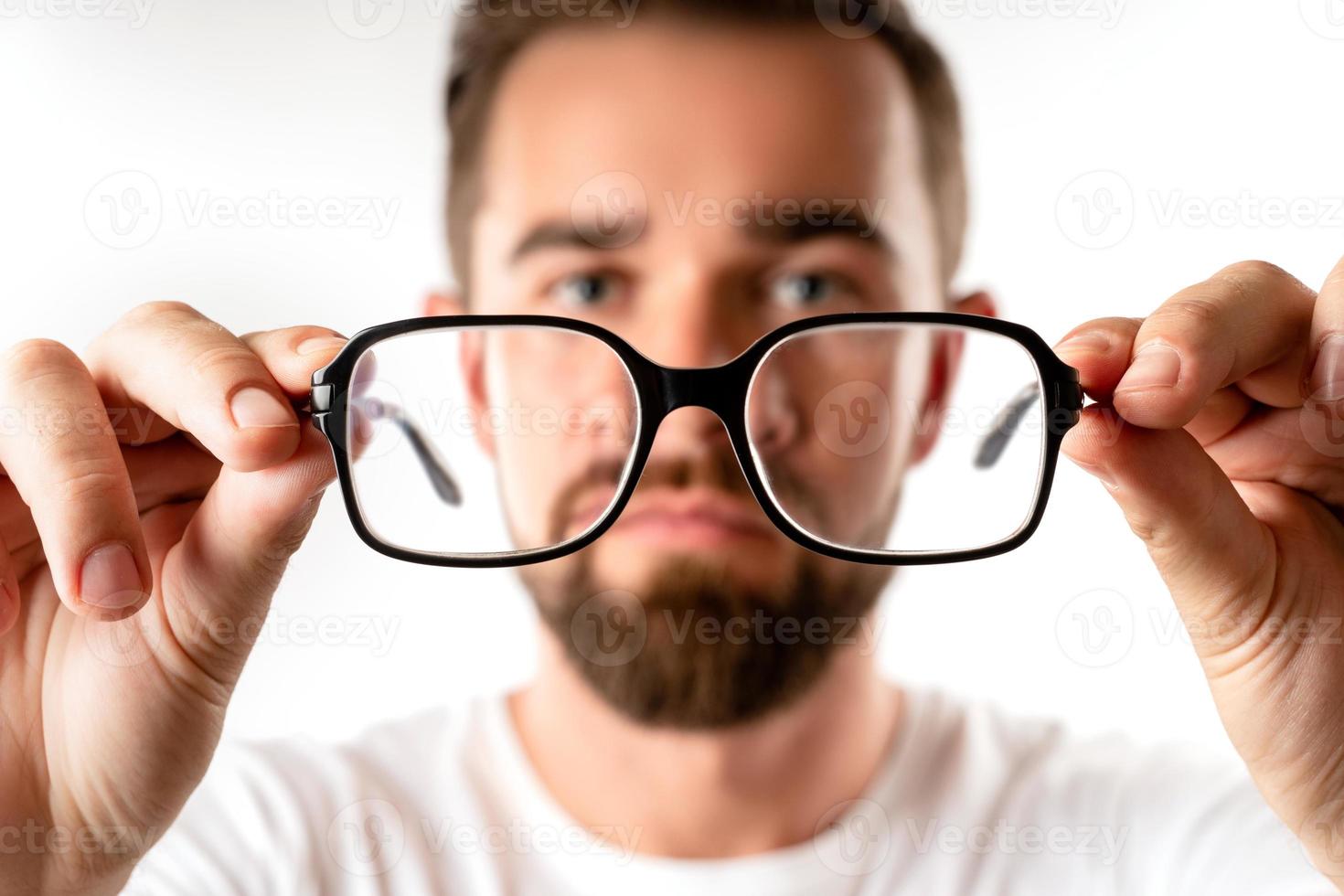 Young man holding eyeglasses in his hands photo