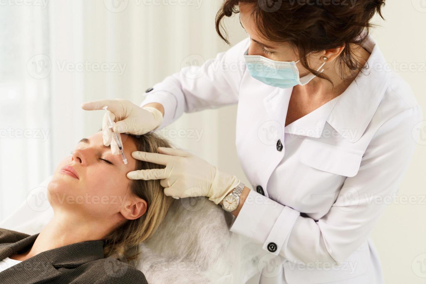 Doctor and client during filler injections in aesthetic medical clinic photo