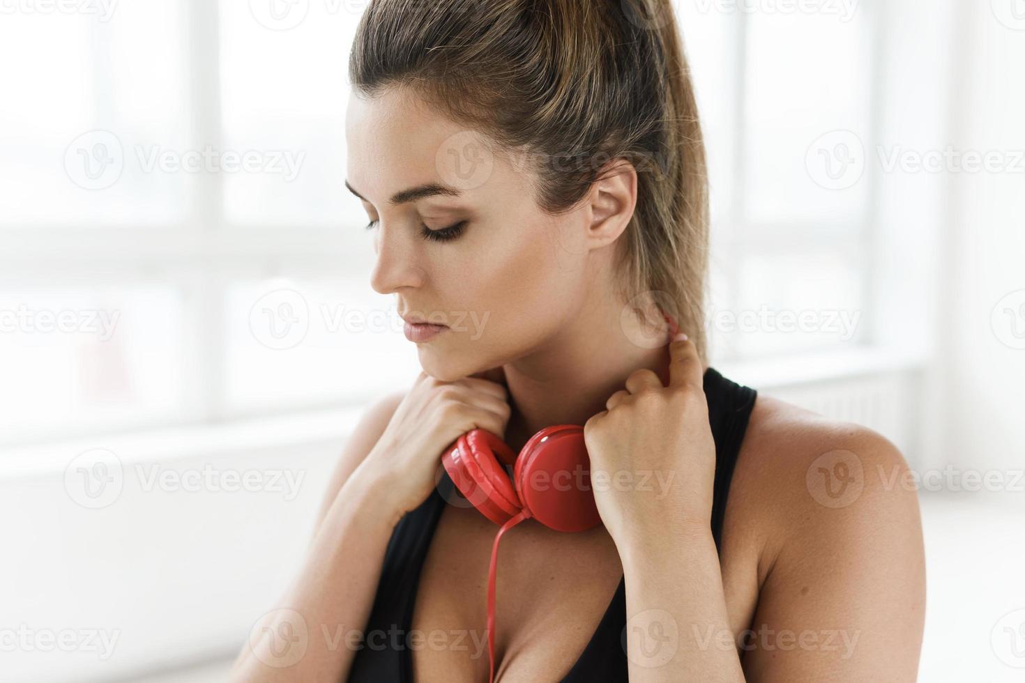 mujer deportiva con auriculares rojos escuchando música para hacer