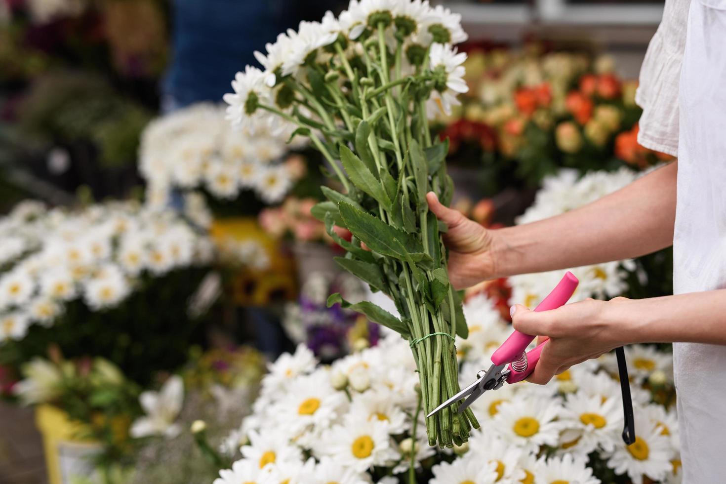 floristería mujer cortando el borde inferior de las flores con tijeras de podar afiladas foto