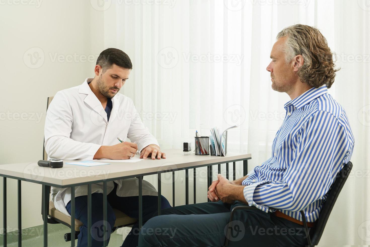 Doctor and middle aged male patient during consultation photo