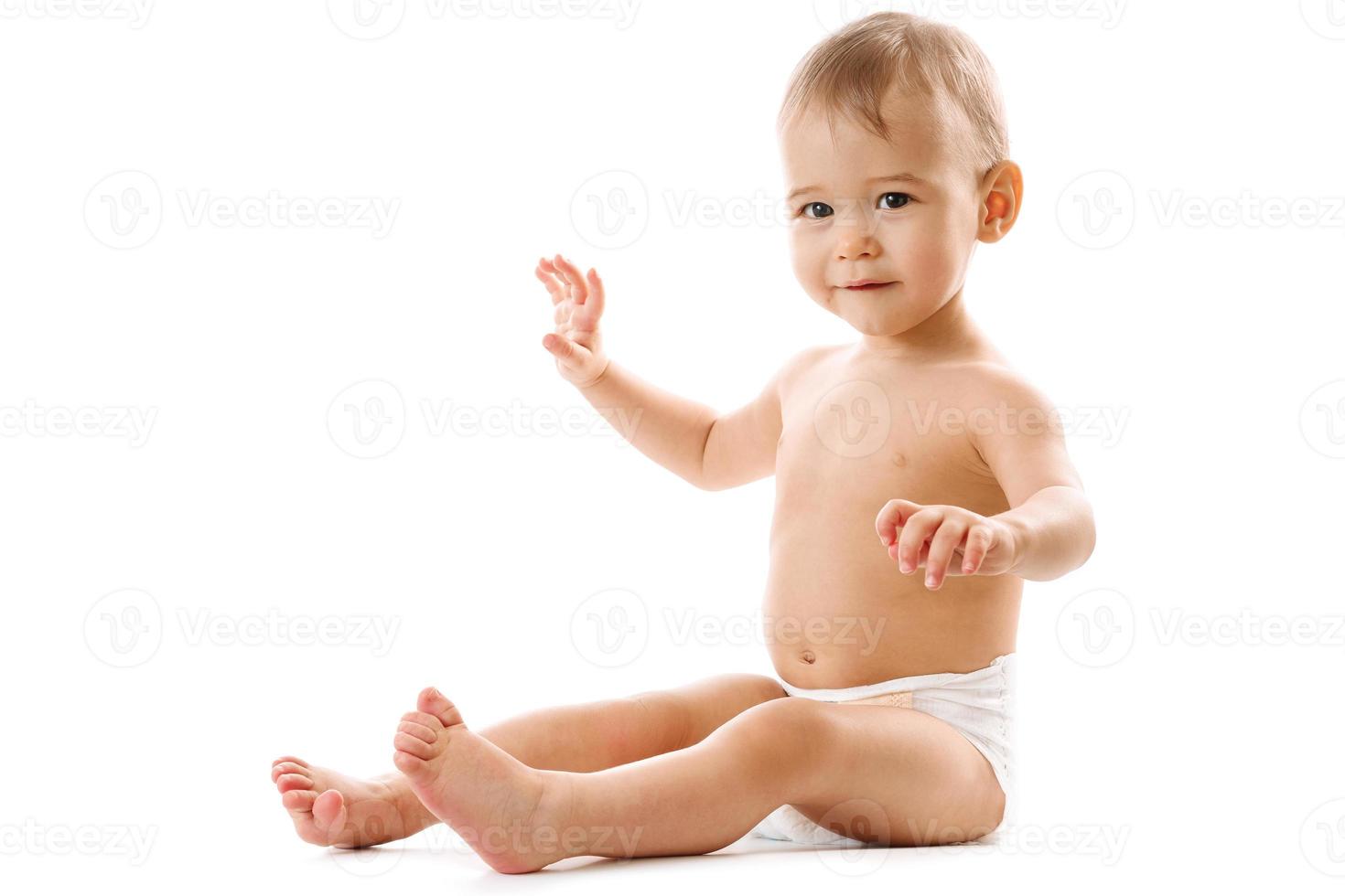 Curious healthy little boy in diaper sitting and smiling. photo