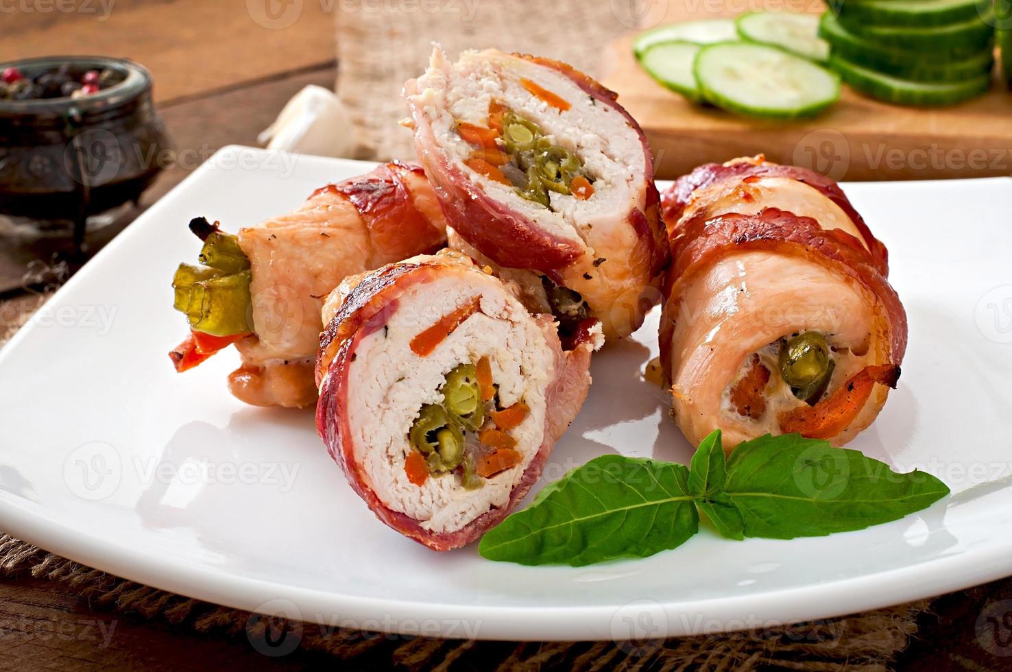 Delicious chicken rolls stuffed with green beans and carrots wrapped in strips of bacon photo
